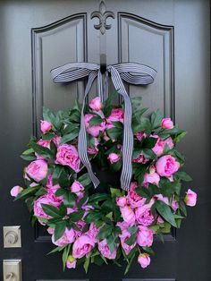 a wreath with pink flowers is hanging on the front door