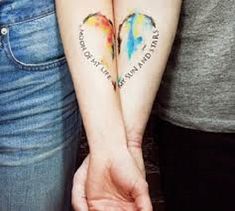 two people are holding hands with tattoos on their arms and the words love is all around them