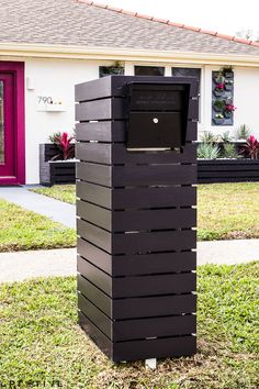 a black box sitting in the middle of a yard next to a red door and house