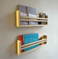 two wooden shelves holding books and folders on the wall next to eachother