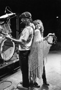 a man and woman standing next to each other in front of a drum on stage