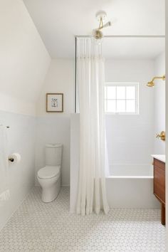 a white bathroom with a shower curtain and toilet