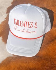 Get ready for game day with the "Tailgates & Touchdowns" trucker hat--a must-have for every fan. Designed with breathable mesh and a comfortable snapback fit, this hat is perfect for long days at the tailgate and cheering in the stands. The bold lettering on the front lets everyone know your priorities: great times and great football. Whether you're rooting for your favorite team or just soaking up the atmosphere, this trucker hat is the ultimate accessory for any football enthusiast. White Usc Hat, White Trucker Hat For Game Day, Game Day White Trucker Baseball Cap, White Trucker Baseball Cap For Game Day, White Trucker Baseball Cap For Fan Gear, White Trucker Baseball Cap For Fans, White Adjustable Trucker Hat For Game Day, White Sports Fan Trucker Hat For Game Day, Game Day Trucker Snapback Hat