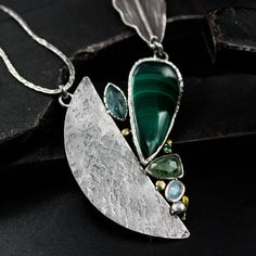 Teadrop Malachite pendant necklace and kyanite, moonstone with silver fan shape on sterling silver chian. Handcraft S-Hook clasp closer Necklace measures: 22.5 inches Pendant measure: 52.5mm W x 63.5 mm H Gemstone measure: 16.5 mm W x 35 mm H SKU: 2Y-9S4G-57K5 Silver Teardrop Necklace In Fusion Style, Silver Teardrop Fusion Necklace, Fusion Style Silver Teardrop Necklace, Silver Fusion Necklace With Gemstone Accents, Silver Teardrop Pendant Necklace With Natural Stones, Silver Drop Necklace With Gemstone Accents, Silver Teardrop Necklaces With Unique Variations, Silver Necklaces With Gemstone Accents, Unique Silver Necklaces With Gemstone Accents