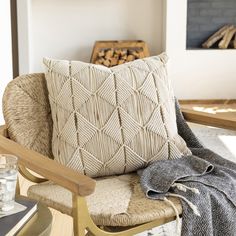 a chair with a blanket on top of it next to a fire place filled with logs