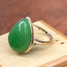 Estate 14KT yellow gold teardrop/ pear, large jade bezel-set band ring. Beautiful, vibrant, dyed green jade! Size 7 Weight: 3.73 grams Band width: 2mm Genuine jade measures: 20mm x15mm Stamped 14KT Excellent estate condition Classic Pear-shaped Green Ring, Classic Green Pear-shaped Ring, Green Teardrop Ring For May Birthstone, Teardrop Green May Birthstone Ring, Green Teardrop May Birthstone Ring, Green Teardrop Emerald Ring For May Birthstone, Classic Green Teardrop Emerald Ring, Green Teardrop Fine Jewelry Ring, Green Teardrop Rings For Anniversary