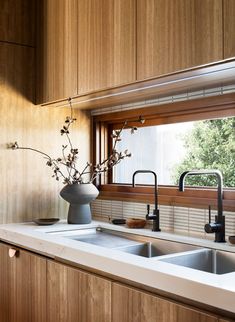 a vase with flowers in it sitting on a kitchen counter next to a sink and window