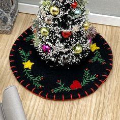 a small christmas tree on a rug in front of a door with ornaments around it