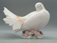 a white bird figurine with pink roses on it