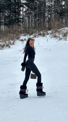 a woman in black is walking through the snow