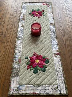 a table runner with a candle on it and a red bowl sitting on top of it