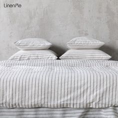 a bed with two pillows on top of it next to a concrete wall and floor