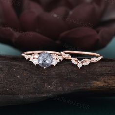 two wedding rings with diamonds on top of a tree branch in front of a flower