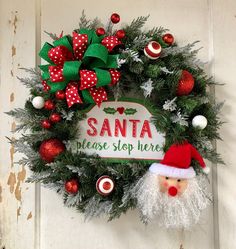 a christmas wreath hanging on the front door with santa's helper and ornaments