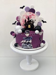 a purple cake with white and black decorations on it's top, sitting on a pedestal