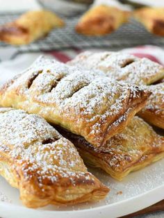 several pastries on a white plate with powdered sugar toppings in the background