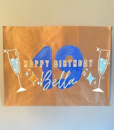 a brown bag with the words happy birthday written in blue on it and champagne flutes