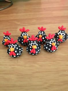 four black and white polka dot decorated chicken figurines on a wooden table top