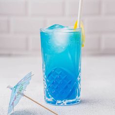 a blue drink in a glass with an umbrella next to it