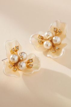 two pairs of pearl and crystal flower earrings on a white surface, with gold - plated accents