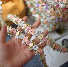 a hand is holding some flowers in front of a box full of other flowered items