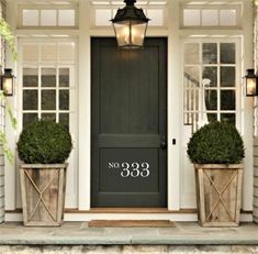 two planters on the front steps of a house with a black door and windows