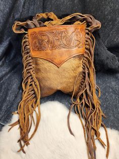 This bag sure is one of a kind and unique. featuring hair on hide and soft Kodiak this western style bag features hand-tied Fringe, bag was hand tooled in a classic western style leather smithing.  CUSTOM ITEMS ARE NON-REFUNDABLE. THERE ARE ZERO EXCEPTIONS TO THIS RULE.  MAKE SURE ALL MEASURMENTS, SIZING,DETAILS AND COLORS AND CLEARLY COMMMUNICATED WITH US. Hardware-Embellishments-Hides-Textures-Coloration may vary depending on what we have in stock to ensure quick and efficient service and deli Hand Tooled Leather Bags For Rodeo, Western Style Brown Bag With Concho, Western Style Rectangular Bag With Adjustable Strap, Western-themed Brown Leather Shoulder Bag, Bohemian Brown Bags With Concho, Western Style Hand Tooled Brown Bag, Western Style Hand Tooled Brown Shoulder Bag, Western Style Brown Hand Tooled Shoulder Bag, Western Style Hand Tooled Shoulder Bag For Travel