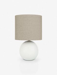 a white table lamp with a beige shade on the base and a light brown linen shade on the top