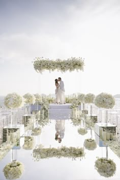 a bride and groom standing in front of an altar with white flowers