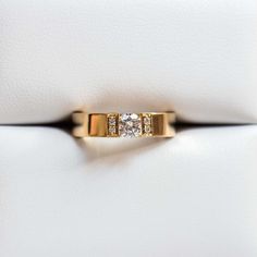 a diamond ring sitting on top of a white bag with gold trim around the band