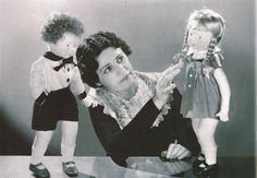 an old black and white photo of a woman holding a doll next to two children