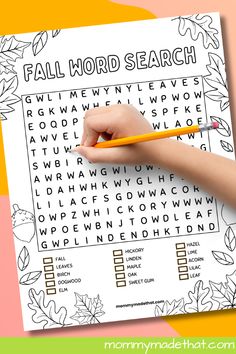 a child's hand holding a pencil and writing on a fall word search page