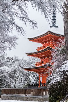 a tall red building surrounded by snow covered trees