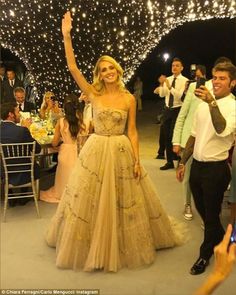 a woman in a long dress is walking down the aisle with her arms raised up