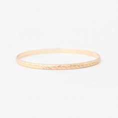 A beautiful bangle that stands out in a stack or makes a statement worn alone. This vintage-style engraving pattern is done by hand by a master engraver in Tennessee. The pattern is reminiscent of a vine or wheat pattern with a delicate milgrain edge. This bangle is sure to be an heirloom passed down for generations. Add custom interior engraving for a personalized touch. A 4mm solid 14k gold half-round bangle with a flat interior. Please email hello@yearlyco.com for any custom engraving request Classic Ceremonial Engraved Bangle, Classic Round Ceremonial Cuff Bracelet, Classic Etched Gold Bracelet, Classic Round Cuff Bracelet For Ceremonial Occasions, Classic Etched Bangle Bracelet, Classic Etched Bangle Bracelets, Classic Engraved Bangle For Ceremonial Occasions, Classic Adjustable Etched Bangle, Ceremonial 14k Gold Engraved Bangle