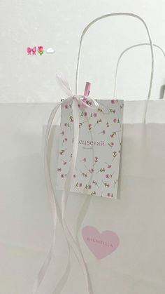 a white bag with pink flowers on it and a heart shaped tag hanging from the handle