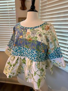 This is a handmade floral blouse sewn with nice blend of upcycled floral fabrics of blue, white, yellow and green colors. The fit of this blouse is an oversized/comfy style with a gathered peplum and wide cut sleeves. Measurements: width - 57 inches. Spring Green Patchwork Blouse, Cotton Tops With Mixed Print, Green Patchwork Cotton Blouse, Green Cotton Patchwork Blouse, Casual Cotton Blouse With Floral Patchwork, White Patchwork Blouse With Relaxed Fit, Green Cotton Blouse With Patchwork, Spring Floral Print Blouse For Gatherings, Floral Print Blouse For Spring Gatherings