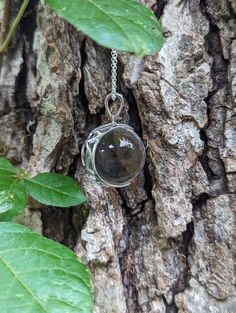 An extra large 20mm crystal clear quartz, tension set in a sterling silver, filigree, crescent moon shaped pendant.   The pendant is polished to a bright, shiny finish. Arrives with the pictured, 24 inch sterling silver rolo chain.  The 8th picture shows the filigree back of the mount. The chain shown is the chain that is included.   There has been no drilling or marring of the quartz whatsoever. The whole quartz sphere is what gives the piece its authenticity. Undrilled whole orbs are the hallm Smoky Quartz Pendant Necklace Gift, Silver Round Crystal Necklace With Moon Charm, Smoky Quartz Pendant Necklace For Gift, Silver Moon Phase Crystal Necklace, Silver Moon Phase Pendant Crystal Necklace, Silver Crystal Moon Phase Pendant Necklace, Silver Pendant Crystal Necklace With Moon Phase, Silver Crystal Necklace With Moon Charm, Elegant Silver Crystal Necklace With Moon Phase