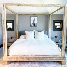 a four poster bed with white linens and pillows on the bottom, in a bedroom