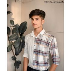 a young man standing in front of a plant