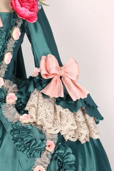 Revel in the grandeur of the past with our Emerald Baroque Style Gown, a resplendent tribute to the rococo and baroque eras. This majestic Victorian Ball Dress, reminiscent of Marie Antoinette's opulent wardrobe, is a symphony of lush emerald green and delicate blush accents. Adorned with artful floral appliqués and ornate lace, each detail is meticulously crafted to evoke the romance of an enchanted garden. The luxurious bows and ruffles are strategically placed to celebrate and flatter a plus- Elegant Green Victorian Dress For Costume Party, Marie Antoinette Style Victorian Dress With Ruffles, Elegant Victorian Dress With Ruffles And Baroque Shape, Pink Rococo Victorian Dress Costume, Pink Rococo Victorian Dress For Costume, Pink Victorian Rococo Dress For Costume, Elegant Green Victorian Costume Dress, Pink Victorian Marie Antoinette Costume Dress, Pink Victorian Dress Costume