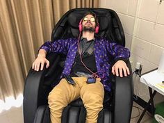 a man with headphones is sitting in a reclining chair and listening to music