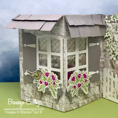 a paper cut out of a house with flowers on the window sill and trees outside