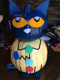 a blue cat sitting on top of a pumpkin with yellow and blue decorations around it