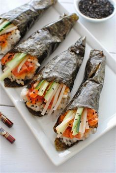 sushi rolls with vegetables and sauce on a white plate next to some chopsticks