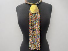 This stunning necklace uses authentic brass and features beautiful multicoloured beads, creating a striking piece with an ethnic feel. The pendant is delicately engraved with intricate details, and the fringe adds a touch of movement to the design. The necklace is perfect for women who love unique and eye-catching jewellery. Its African origins and cultural significance make it an ideal addition to any collection, adding a touch of style and elegance to any outfit. Material: Beads and decorative Adjustable Multicolor Necklace With Gold Beads, Traditional Multicolor Beaded Fringe Necklaces, Traditional Multicolor Beaded Necklaces With Fringe, Artisan Multicolor Beaded Necklaces With Fringe, Traditional Beaded Fringe Necklace, Traditional Multicolor Beaded Necklace With Fringe, Traditional Multicolor Jewelry With Gold Beads, Artisan Multicolor Beaded Necklace With Fringe, Bohemian Tassel Necklace With Beaded Chain