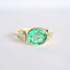 Item Details: 2.43 ct. natural Colombian Emerald vibrant light green color. Six round brilliant-cut diamonds weighing 0.06 ct (F/VS) Two trillion-shaped diamonds weighing 0.82 ct. (E/VS) Set in 18K yellow gold This ring is made with a one-of-a-kind center stone. To create a similar ring email custom@berlingerrings.com. Enquire about this ring Design a custom piece with us Gia Certified Oval Green Diamond Ring, Green Oval Diamond Ring Fine Jewelry, Green Oval Diamond Ring, Gia Certified Oval Green Emerald Ring, Gia Certified Oval Emerald Ring, Gia Certified Green Oval Emerald Ring, Green Emerald Oval Diamond Ring, Green Oval Diamond Ring With Center Stone, Oval Tsavorite Diamond Ring In Green