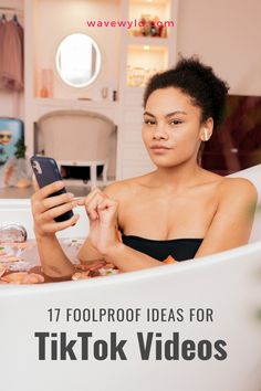 a woman sitting in a bathtub holding a cell phone and looking at the screen