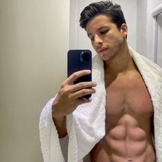 a shirtless man taking a selfie in the bathroom with his phone and towel