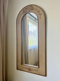 a mirror hanging on the side of a wall next to a window with sheer curtains